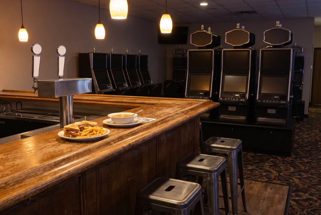 A short wooden bar counter with steel stools, a sandwich with fries and a bowl of soup.